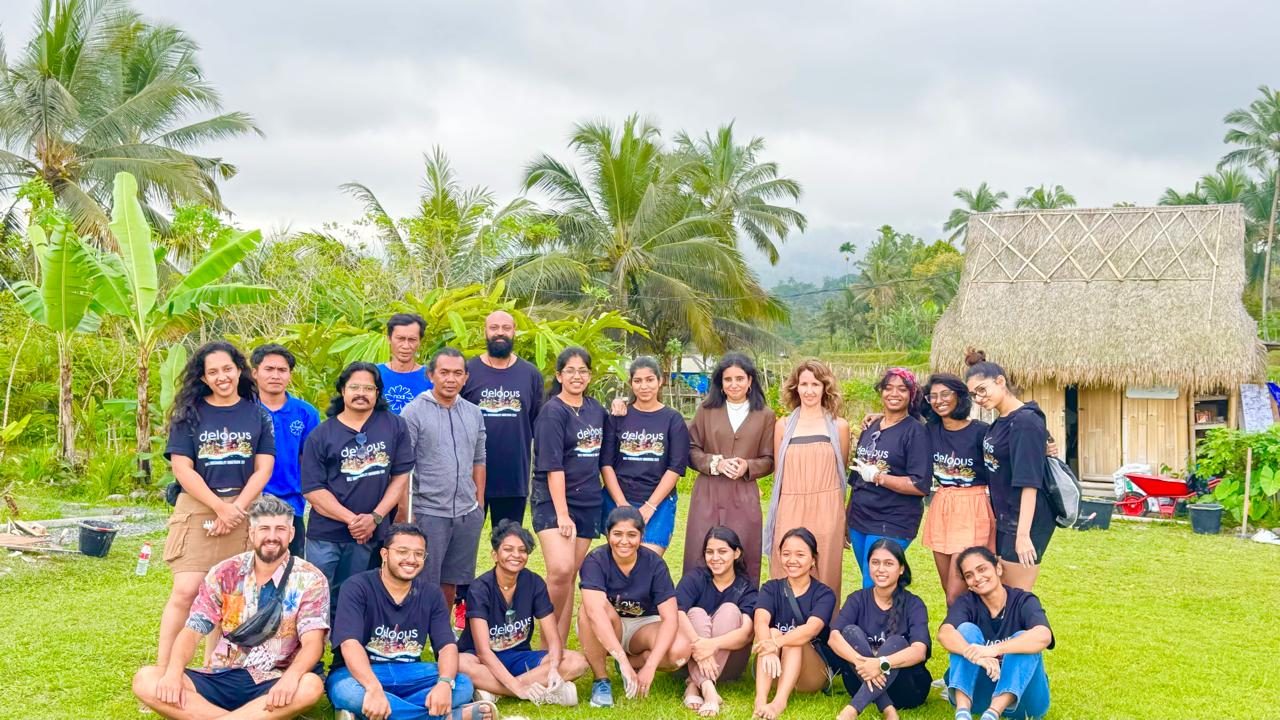Workshop group photo on a lawn beside a thatched bamboo hut at Earth Studio Bali