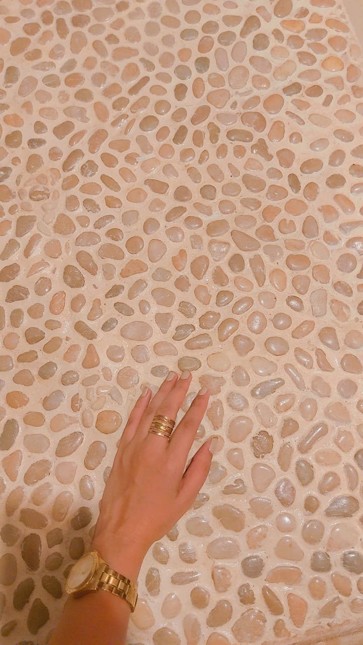 A hand resting on a lime and river pebble finish